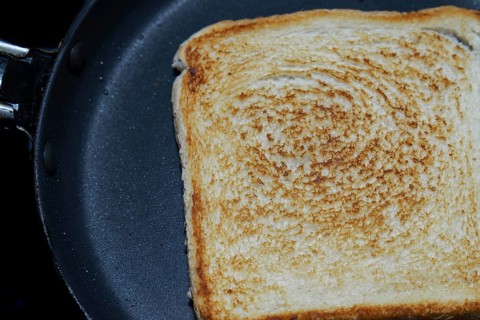 Close-up of a single slice of toasted white bread in a frying pan, showing the texture and