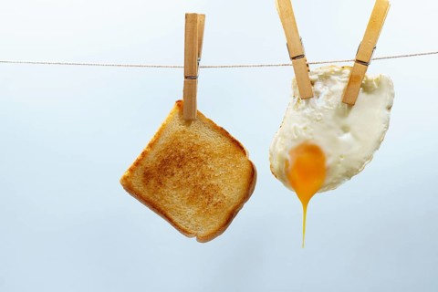 Toast and fried egg hanging from a clothesline with clothespins, representing a simple and