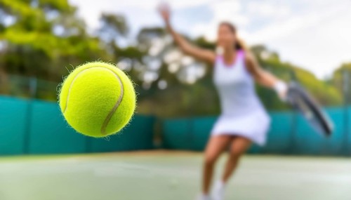 AI generated image showing a flying tennis ball closeup and female player in court ambiance