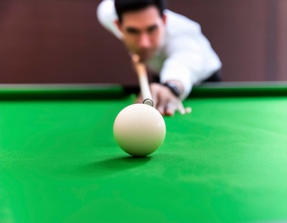 AI generated image showing a billiards table closeup with player and cue ball