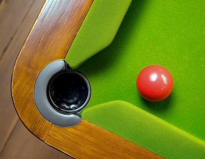 AI generated image showing a billiards table closeup with ball and pocket seen from above