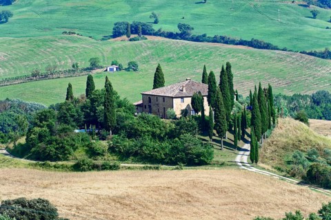 A Tuscan farmhouse surrounded by cypress trees on a hill in a rural setting, south of Pienza,
