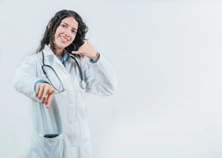 Beautiful female doctor gesturing call isolated. Woman doctor making call gesture and pointing at