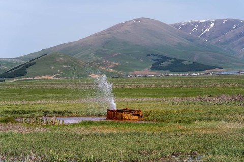 A tranquil landscape with hills and a water fountain in a green meadow, geyser near Karmravan,