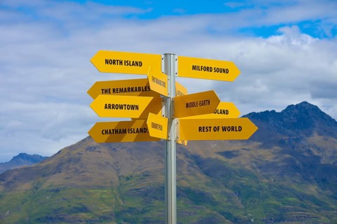Yellow signpost in a mountain landscape, showing directions to different places, Queenstown,