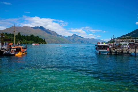 Boats on a jetty with a view of the surrounding mountains and blue water, Queenstown,