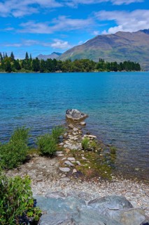 Rocks on the shore of a lake with mountains in the background and a clear atmosphere, Queenstown,