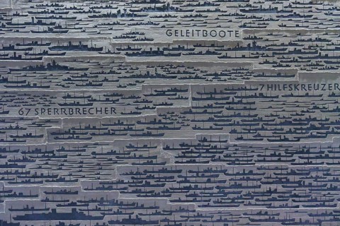 Large number of ship silhouettes on grey metal plate with German texts on ship types, naval