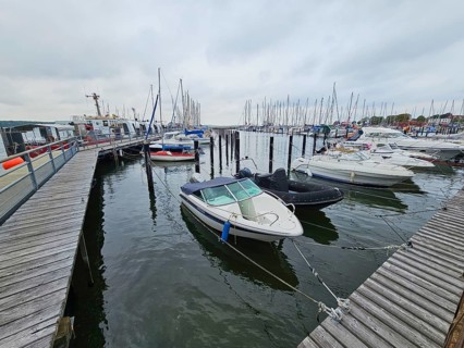 Several motorboats are moored in a harbour, surrounded by jetties and under an overcast sky, Laboe,