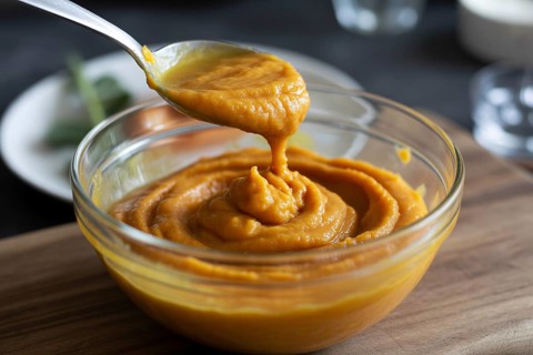 Bowls of creamy pumpkin purée with spoon. Generative ai, AI generated