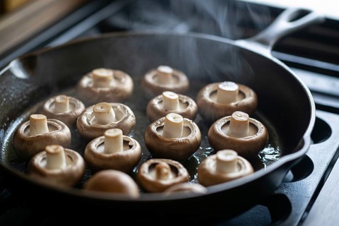Champignon mushrooms sizzling in frying pan with steam. Generative ai, AI generated