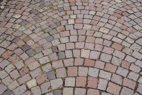 Floor covering made of paving stones with an arched pattern in grey and reddish tones, background,