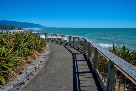 A walkway with railings offers a wide view over the sea and the coastline, Pancake Rocks, Westport,