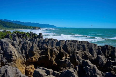 Rough sea meets impressive stacked cliffs under a vast sky, Pancake Rocks, Westport, Greymouth,