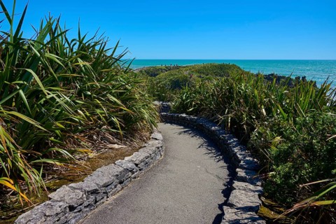 Sea view along a winding road through a green landscape, Pancake Rocks, Westport, Greymouth, West