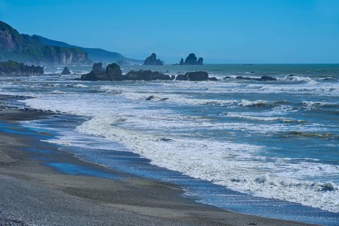 Stormy waves crash against an unspoilt coastline with striking rock formations, West Coast, South