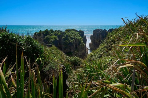 Cliffs with lush plants provide a view of the open sea and clear sky, Pancake Rocks, Westport,