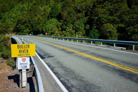Road leads over bridge at Buller River, surrounded by forest and traffic signs, Buller River,