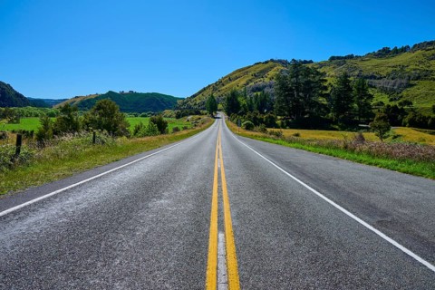 Straight country road with green hills and blue sky, peaceful natural scenery, Buller River,