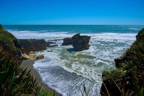 Breathtaking coastal landscape with rocks in the sea under a bright blue sky, Pancake Rocks,