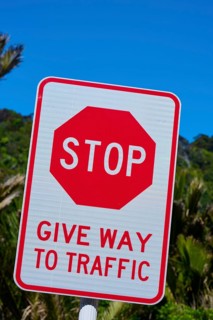 Stop sign indicating give way on a road under a clear blue sky, Pancake Rocks, Westport, Greymouth,