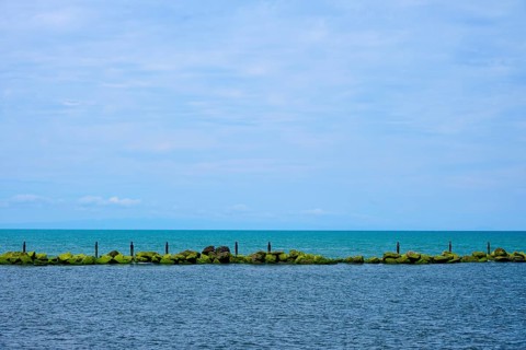 View of the sea with a row of rocks and calm blue sky, Mana Bay, Patea, Taranaki, North Island, New