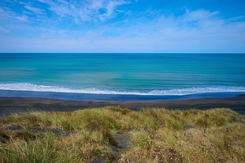 Panoramic view of the endless sea with grassy coastline and gentle waves under a clear sky, Mana