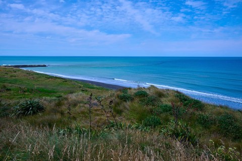 White sandy beach with grassy coastline and gentle waves under a cloudy sky, Mana Bay, Riverview