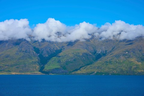 Mountains with a wreath of clouds over a blue lake under a clear sky, Drift Bay, Lake Wakatipu,