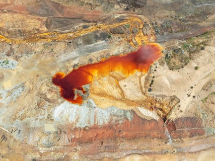 Old mining site and deep orange-red hues in the water of a pool in the mineral-rich area of the Rio