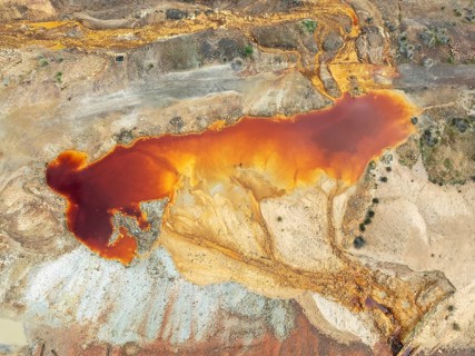 Deep orange-red hues in the water of a pool in the mineral-rich area of the Rio Tinto mines. The