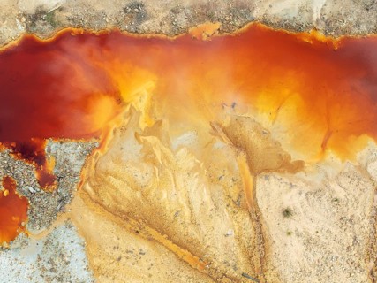 Deep orange-red hues in the water of a pool in the mineral-rich area of the Rio Tinto mines. The