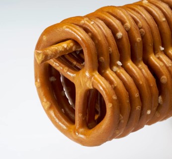 Some lye pretzels hanging on a salt stick in a row in light back