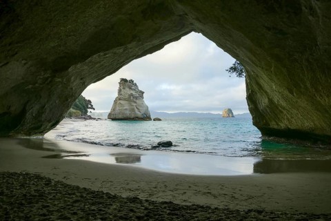 Te Hoho Rock seen through a rock arch at a coastal area named Cathedral Cove in the southern part