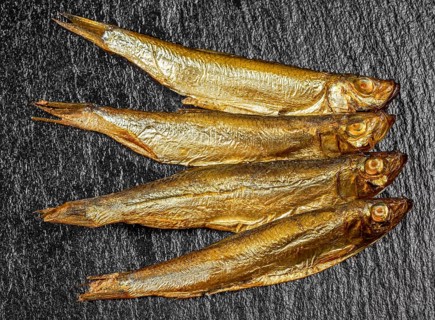 Arrangement with fresh smoked sprats on dark stone slab