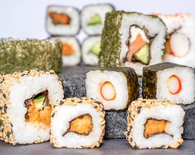 Various sushi dishes on dark grey stone surface