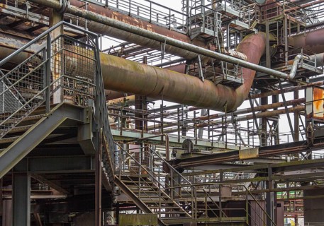 Weathered rundown industrial scenery with old corroded steel girders, stairs and metal tubes