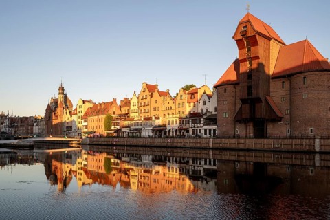 Waterfront promenade with reflection at sunrise in the Old Town, Brama Zuraw crane gate, Motlawa