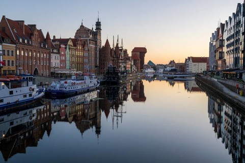 Waterfront promenade with reflection at sunrise in the Old Town, Brama Zuraw crane gate, Motlawa