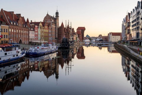 Waterfront promenade with reflection at sunrise in the Old Town, Brama Zuraw crane gate, Motlawa