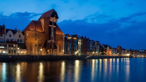 Illuminated waterfront promenade at sunset in the Old Town, Brama Zuraw crane gate, Motlawa River,