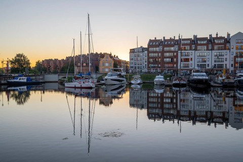 Waterfront promenade with reflection at sunrise in the old town, Motlawa river, boat harbour,