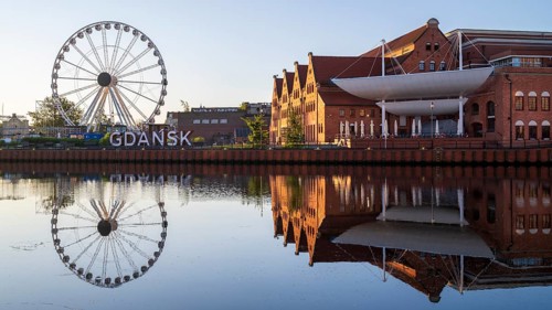 Ferris wheel on the waterfront with reflection at sunrise in the old town, Motlawa River, Gdansk,