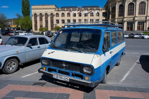 A blue van parked in front of a classic building under a clear sky, car RAF-2203 Latvija, nicknamed