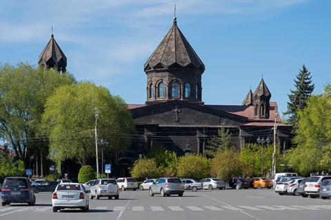 A black church with old architecture and parked cars in a green setting, Cathedral of the Holy