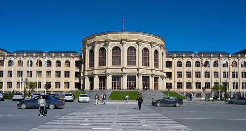 A large town hall with a classical façade, people and cars under a clear sky, Gyumri, Gyumri,