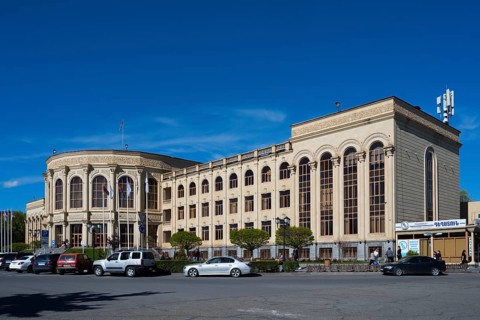 Large historic building in the city centre under a blue sky with parked cars, Gyumri, Gyumri,