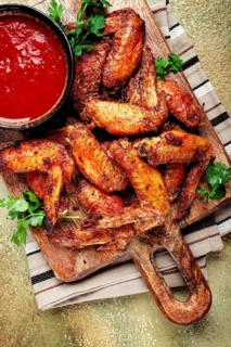Fried in the oven, chicken wings, with spices, tomato sauce, on a cutting board, gray background,