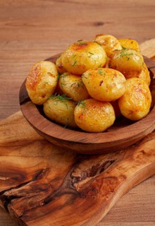 Baked new potatoes, with butter and dill, on a wooden plate, homely, rustic, no people
