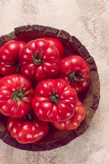 Pink tomatoes, in a rustic wooden bowl, close-up, no people